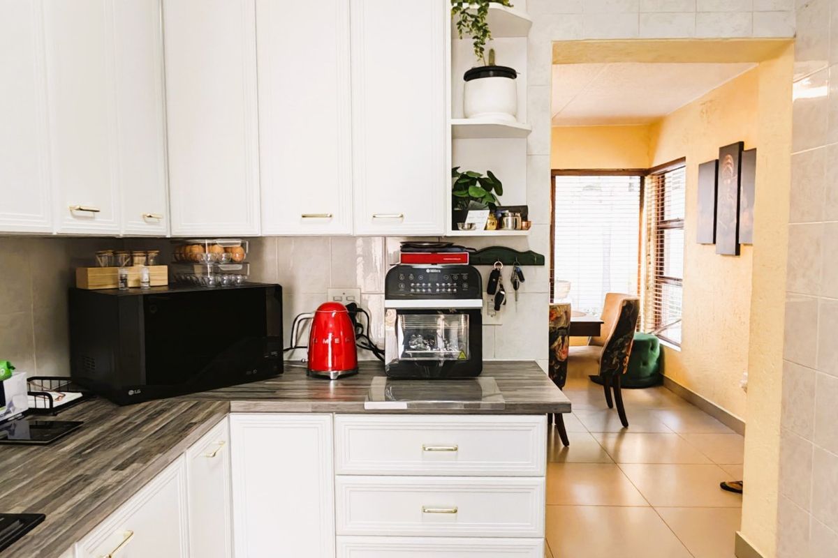 A functional kitchen featuring white cabinetry, laminate countertops, and a tiled backsplash, with an open transition to the adjacent dining area.