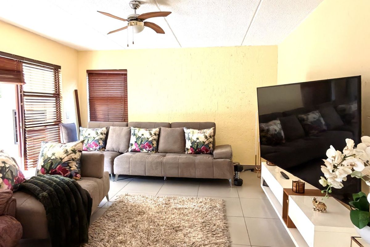 A living room featuring tiled flooring, a ceiling fan, and sliding glass doors that provide access to the outdoor area.