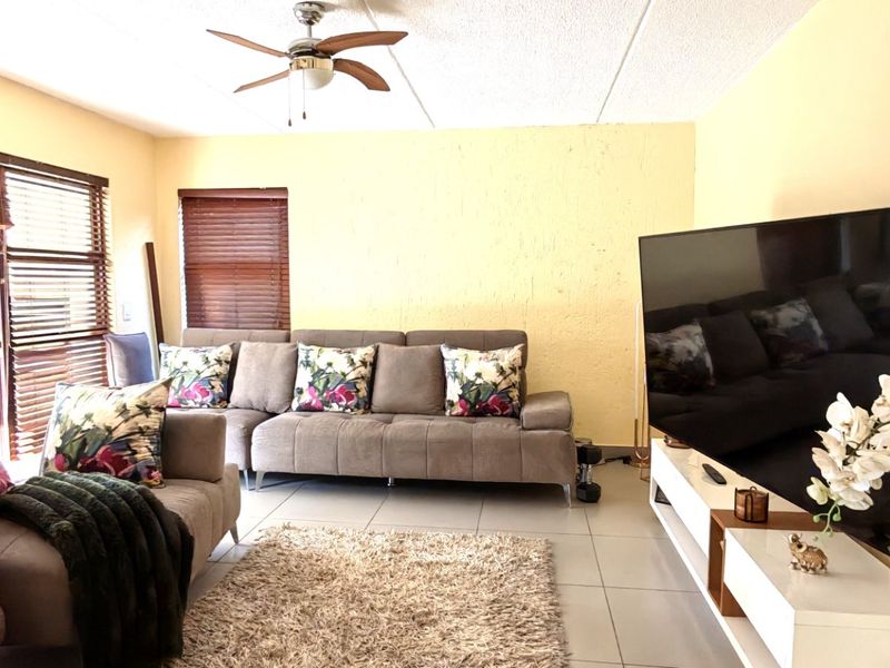 A living room featuring tiled flooring, a ceiling fan, and sliding glass doors that provide access to the outdoor area.