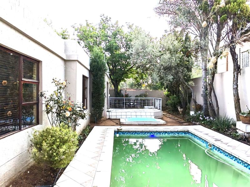Rear garden area featuring a swimming pool with tiled surround, a raised patio section with metal railing, and established perimeter boundary walls.