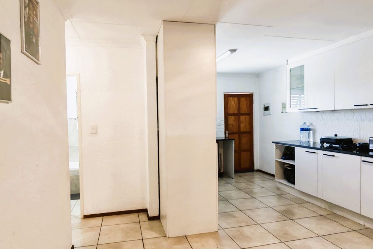 A functional kitchen featuring white built-in cabinetry, dark countertops, and tiled flooring, with an adjacent doorway leading to another area of the home.