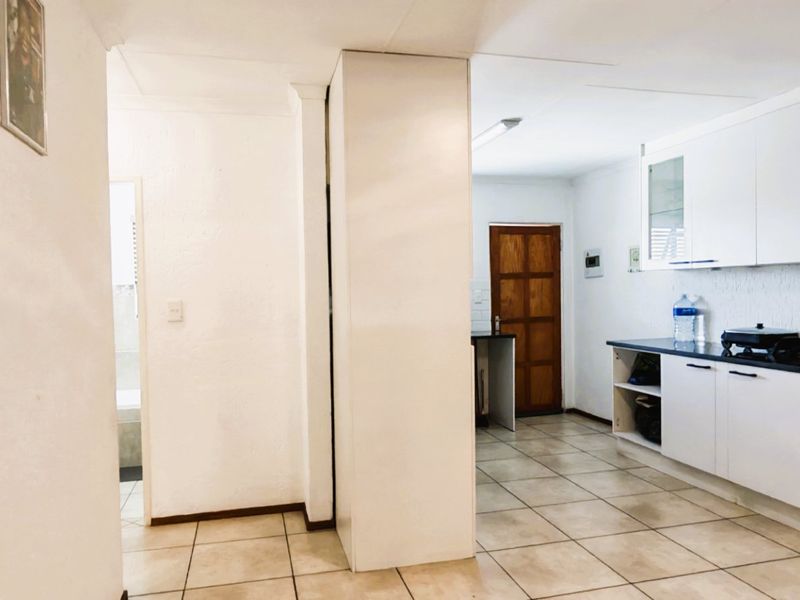 A functional kitchen featuring white built-in cabinetry, dark countertops, and tiled flooring, with an adjacent doorway leading to another area of the home.