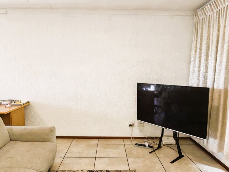 A living room area featuring tiled flooring and neutral wall finishes, providing a functional space ready for modernization and updated interior styling.