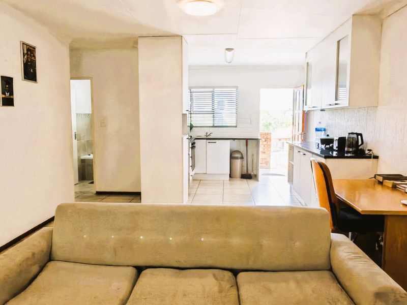Open plan living area featuring a functional kitchen with built-in cabinetry and tiled flooring, leading towards an exterior access point.