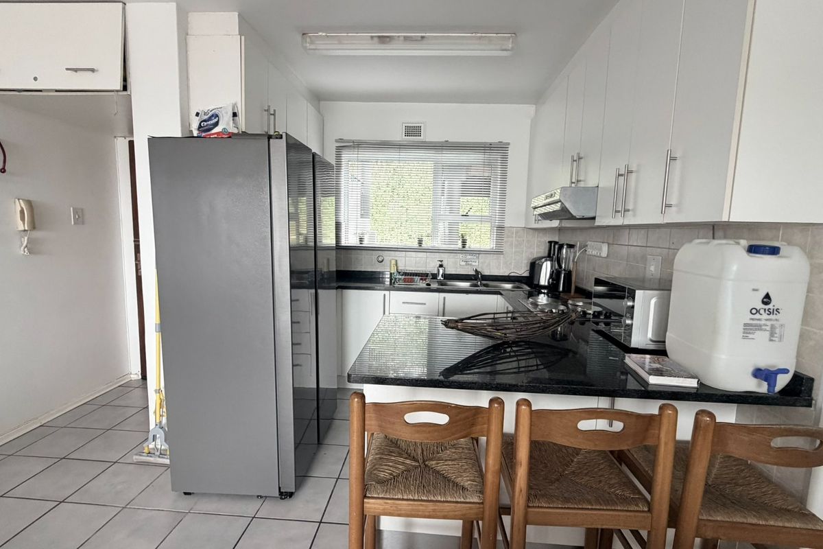 A functional kitchen featuring granite countertops, ample built-in cabinetry, a breakfast bar, and tiled flooring, offering a practical layout for daily use.