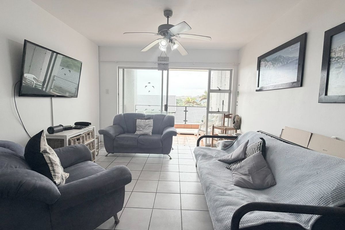 A living room featuring tiled flooring, a ceiling fan, and large sliding glass doors that provide access to an outdoor balcony area.