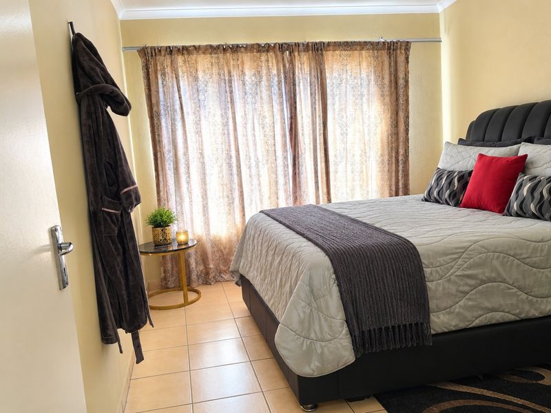 A bedroom featuring tiled flooring, coved ceilings, and a curtain rod, providing a functional space with neutral wall tones.