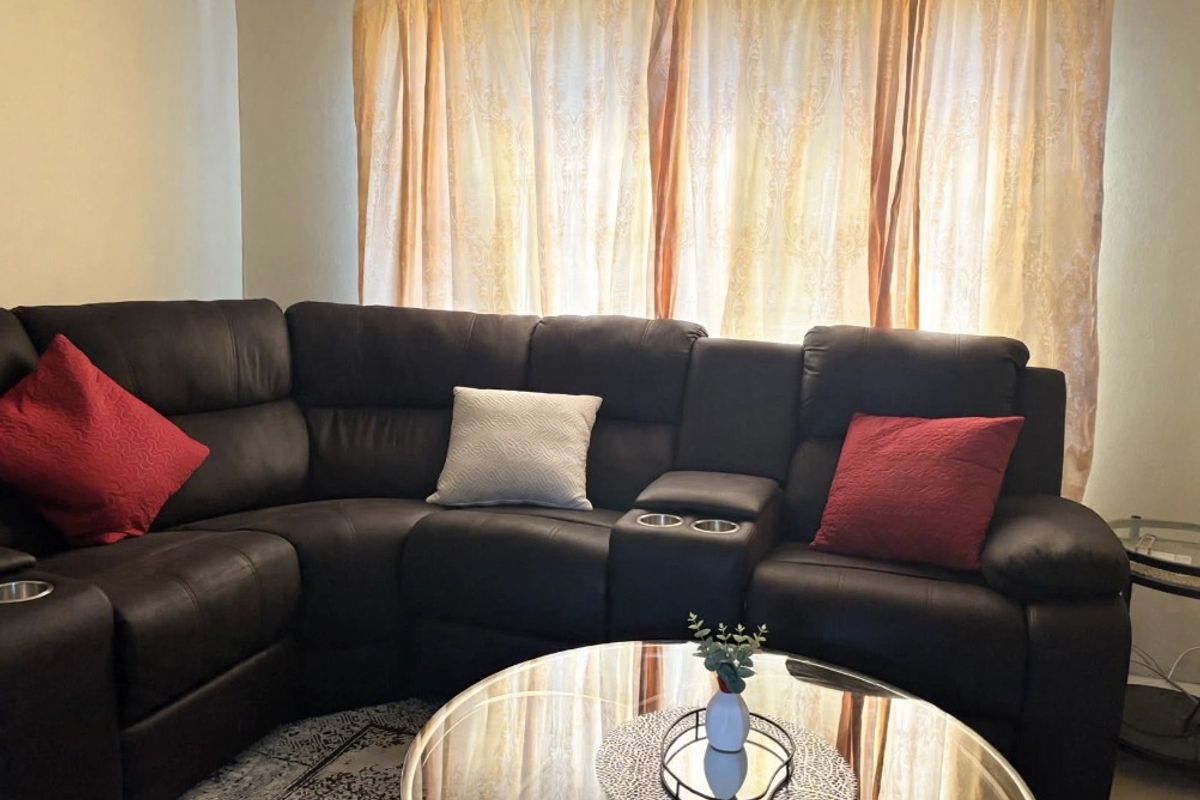 A living room area featuring neutral wall finishes and window treatments, providing a comfortable space for relaxation.