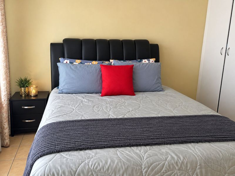 A bedroom featuring tiled flooring and a built-in wardrobe with neutral wall finishes.