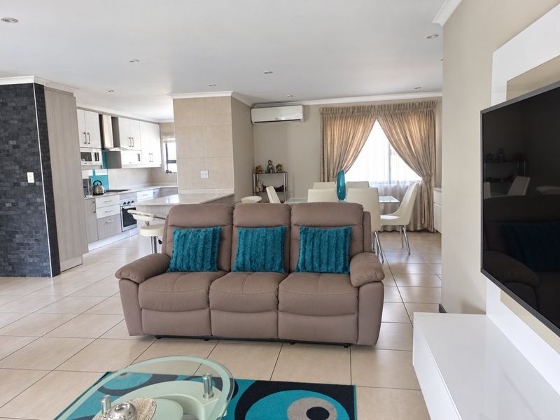Spacious open-plan living area featuring tiled floors, recessed lighting, and a modern kitchen with built-in cabinetry, stone countertops, and integrated appliances.