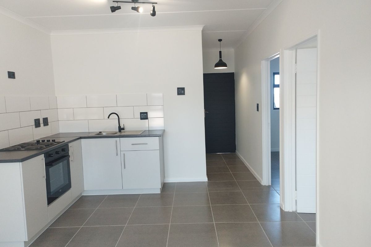 Modern kitchen featuring white cabinetry, subway tile backsplash, built-in oven, gas hob, and neutral tiled flooring in an open-plan layout.