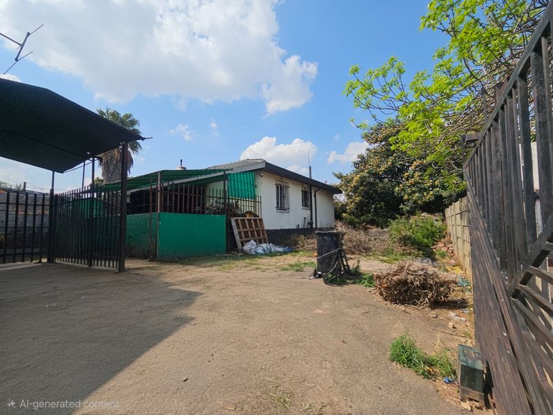 Rear exterior view of the property featuring a carport, security bars on windows, and a large yard area requiring landscaping and maintenance.