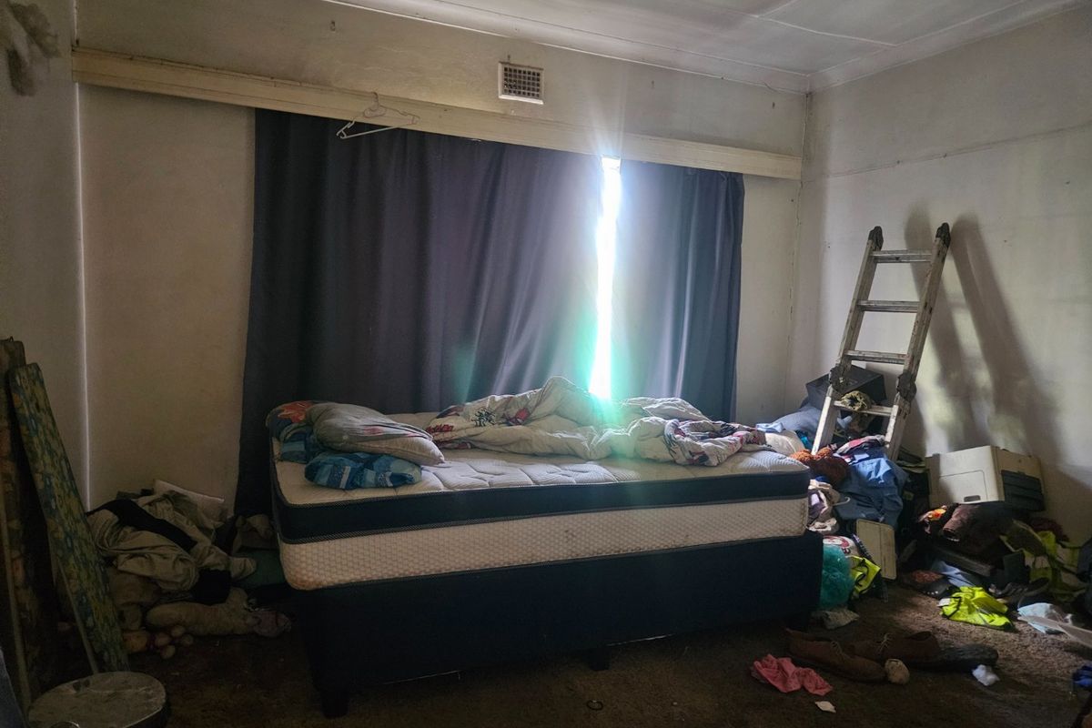 A bedroom space requiring significant renovation, featuring basic wall finishes and ventilation, currently in poor condition and needing cosmetic updates.