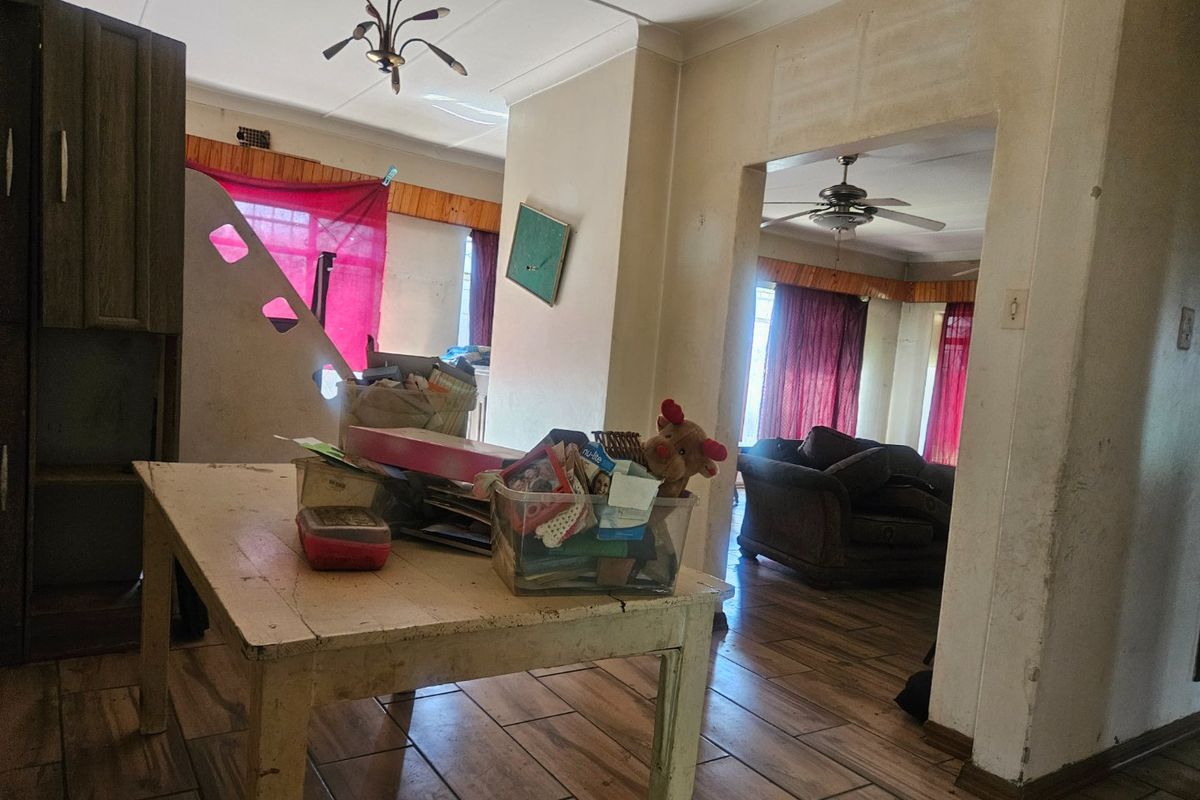 Open-plan living area featuring tiled flooring, ceiling fans, and coved ceilings, requiring cosmetic updates to improve the overall aesthetic and finish.