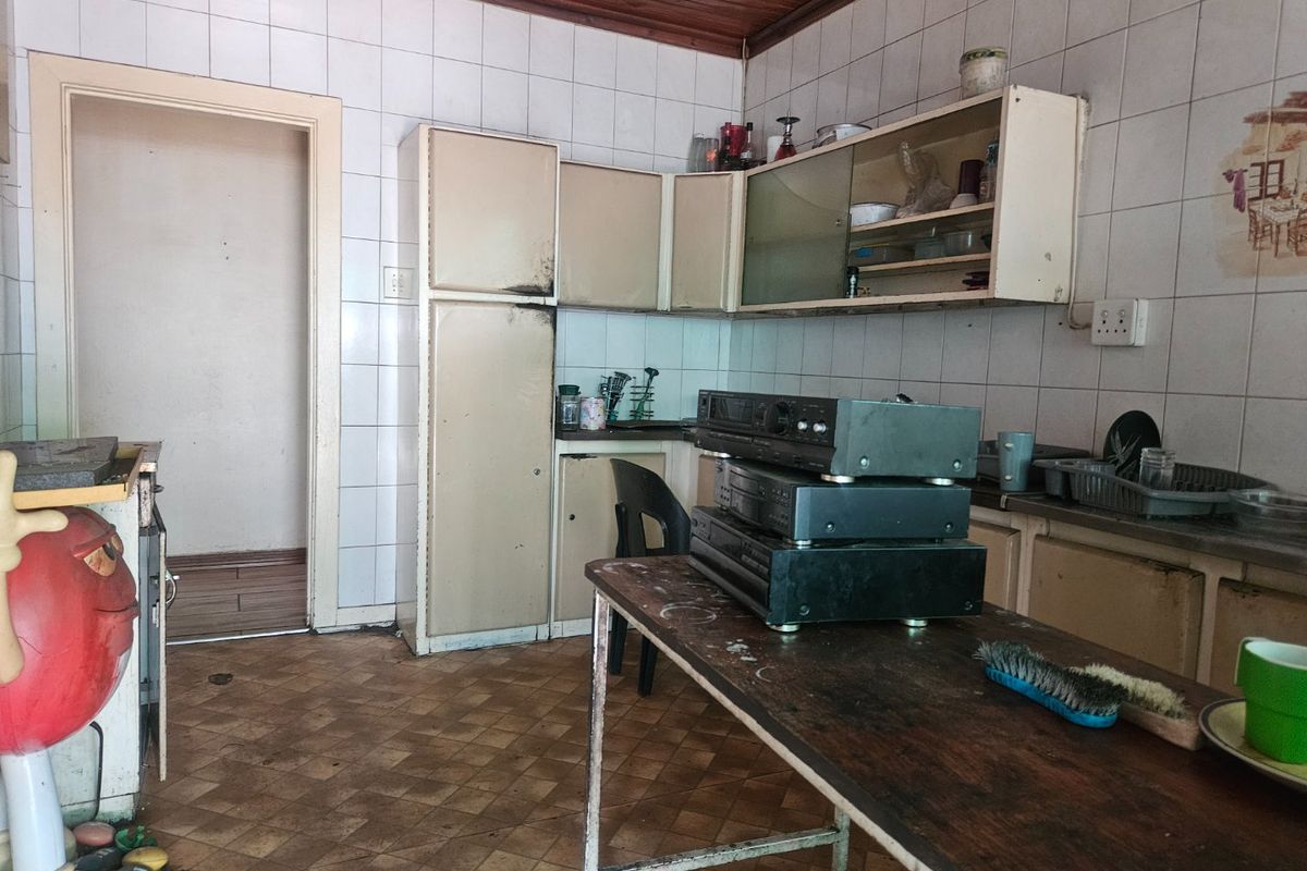 A dated kitchen featuring original built-in cabinetry, tiled walls, and timber ceiling, requiring modernization and renovation to improve functionality and aesthetic appeal.
