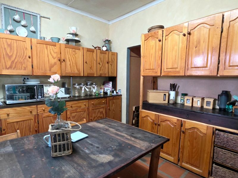 A rustic kitchen featuring extensive wooden cabinetry, terracotta floor tiles, and a functional layout with ample storage space.