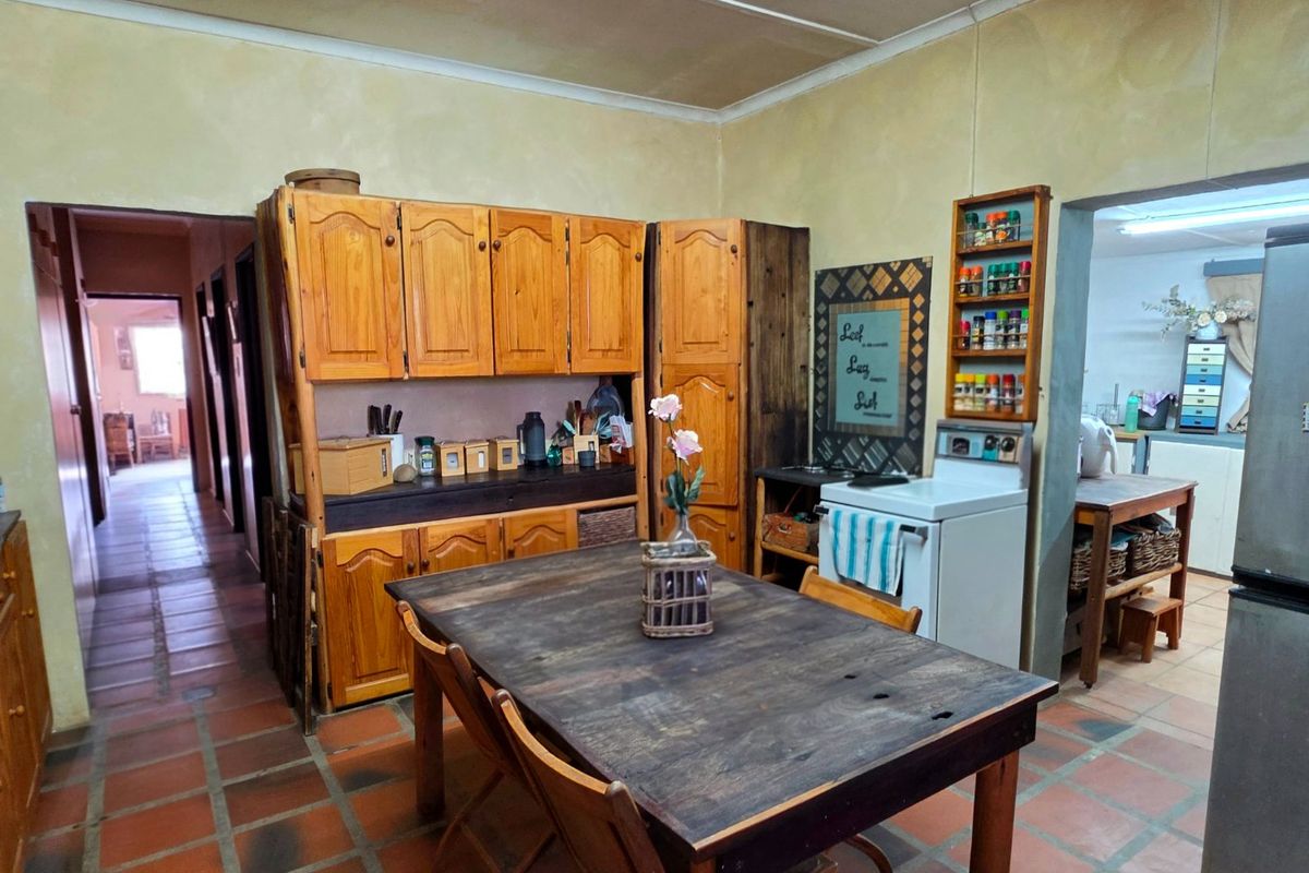 A rustic kitchen featuring wooden cabinetry, a freestanding stove, and terracotta floor tiles, offering a traditional aesthetic with potential for modern updates.