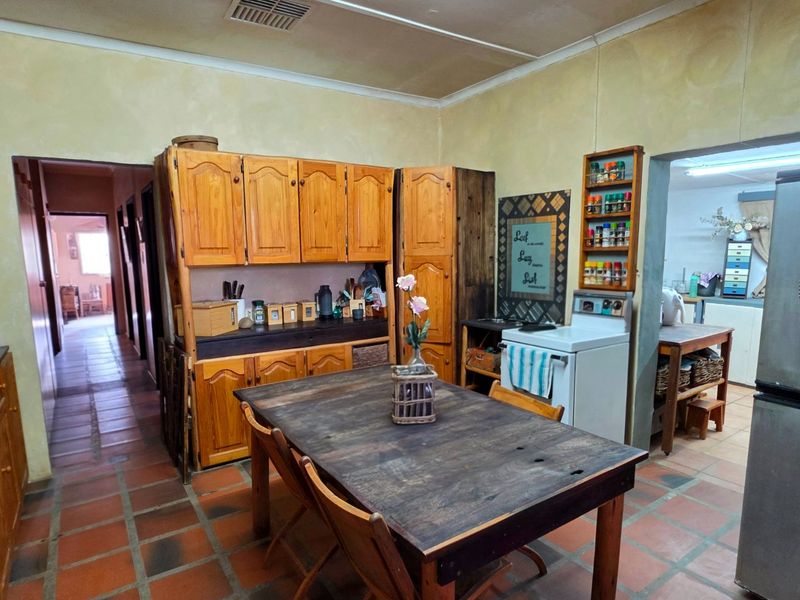 A rustic kitchen featuring wooden cabinetry, a freestanding stove, and terracotta floor tiles, offering a traditional aesthetic with potential for modern updates.