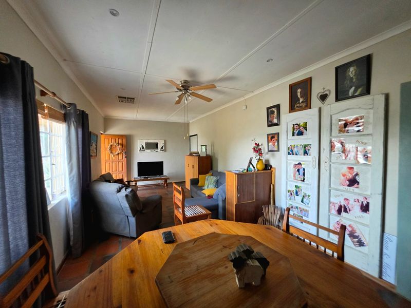 Open-plan living and dining area featuring terracotta floor tiles, a ceiling fan, and neutral wall finishes.
