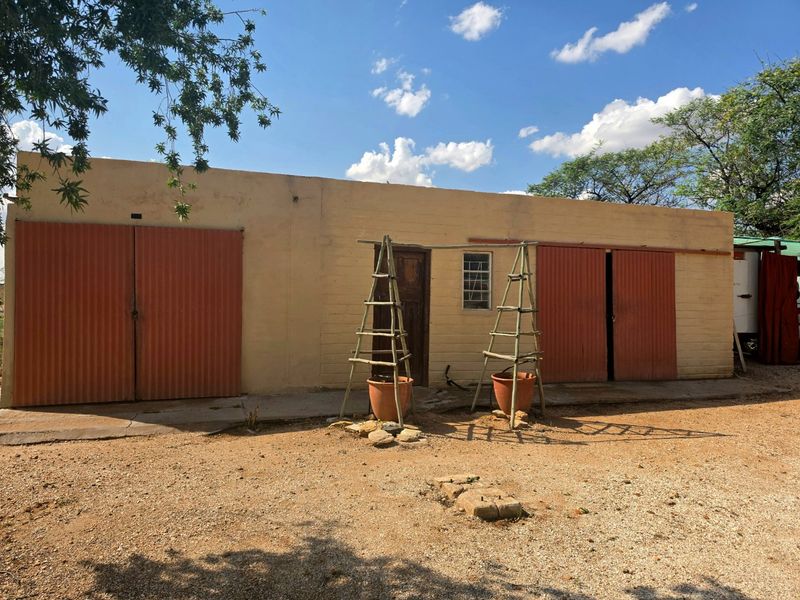 Rear view of a single-story outbuilding or garage featuring corrugated metal doors, masonry walls, and a concrete apron.