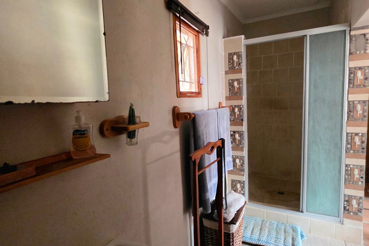 A functional bathroom featuring a shower enclosure with decorative tiled accents, tiled flooring, and a wall-mounted mirror.