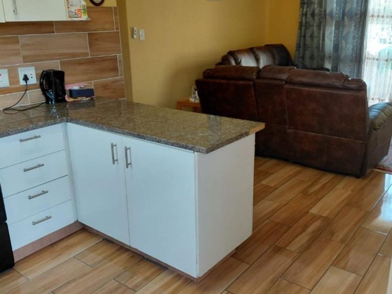 Open plan living and kitchen area featuring tiled flooring, granite countertops, and built-in cabinetry, creating a functional and connected living space.