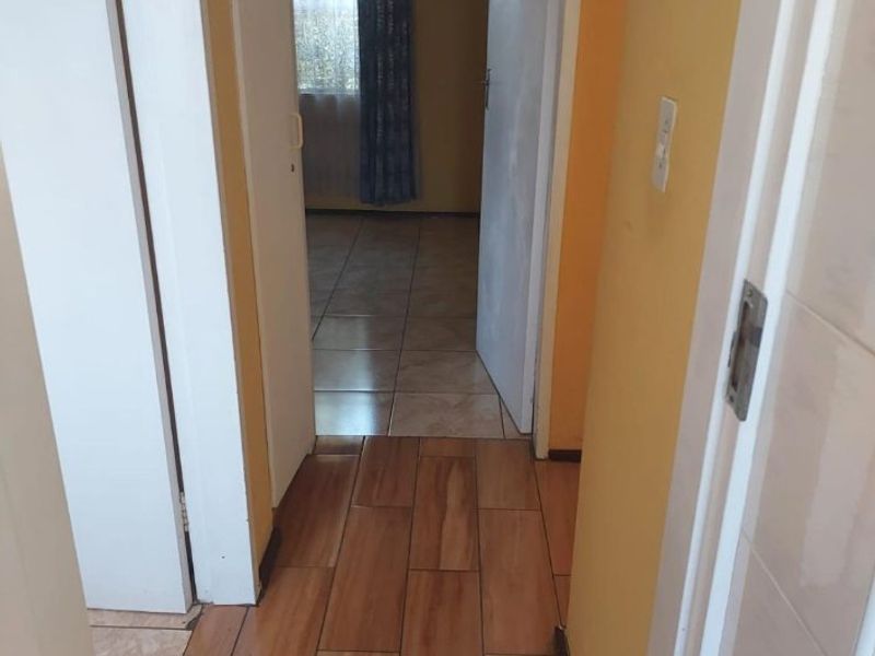 A functional hallway featuring wood-look tiled flooring, connecting to adjacent rooms with standard internal doors.