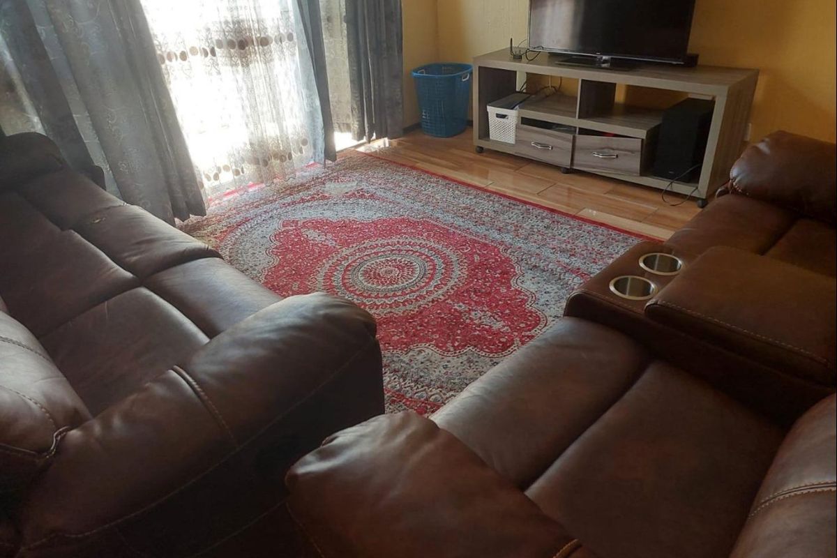 A living room featuring laminate flooring and a sliding glass door providing natural light.