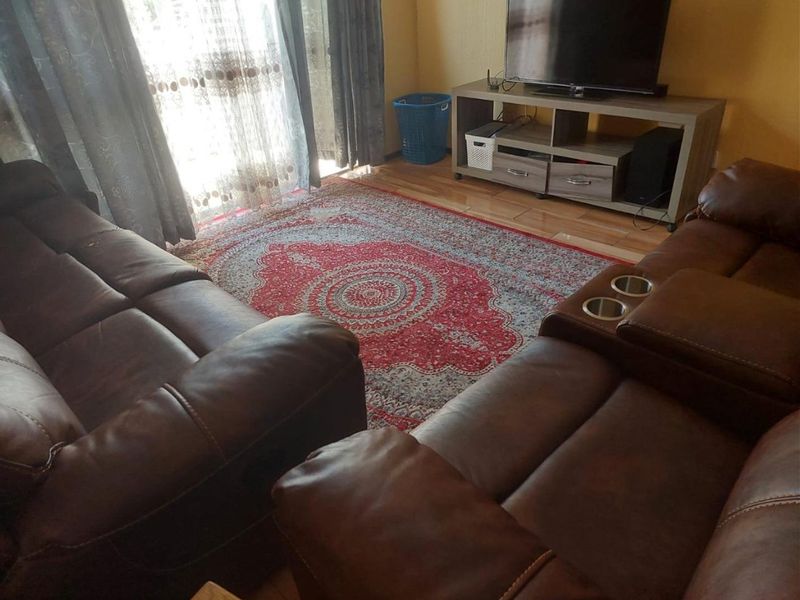A living room featuring laminate flooring and a sliding glass door providing natural light.