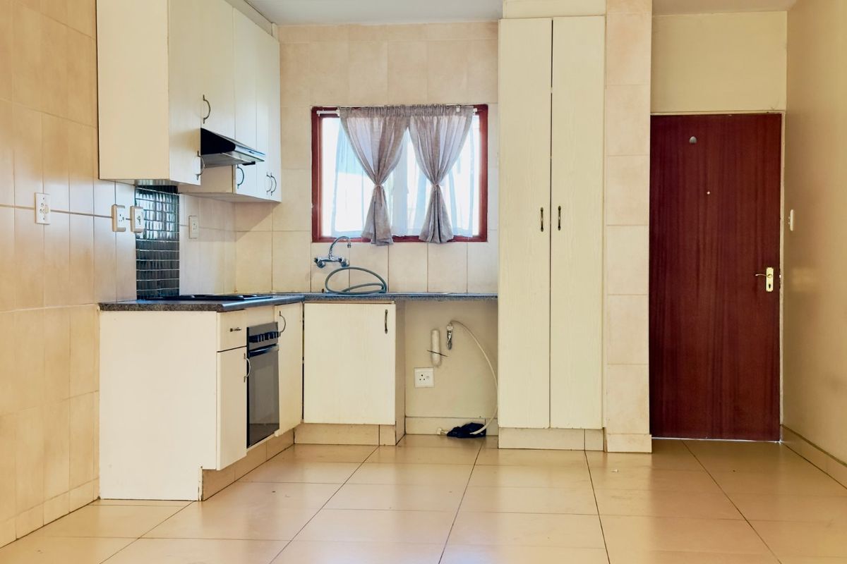 A functional kitchen featuring built-in cabinetry, tiled flooring, a built-in oven, and a tiled backsplash, offering a clean and practical layout.