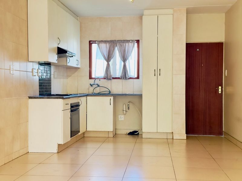 A functional kitchen featuring built-in cabinetry, tiled flooring, a built-in oven, and a tiled backsplash, offering a clean and practical layout.