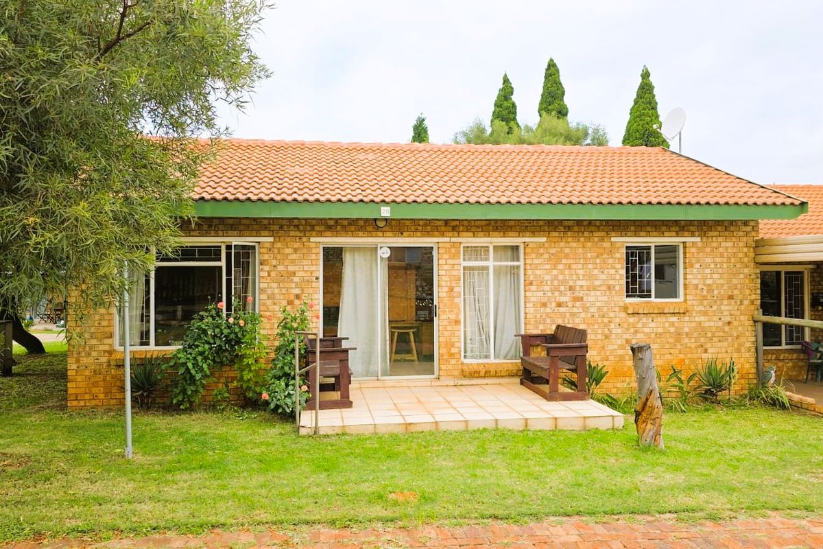Rear view of a face brick house featuring a tiled roof, a small tiled patio, and sliding glass door access.