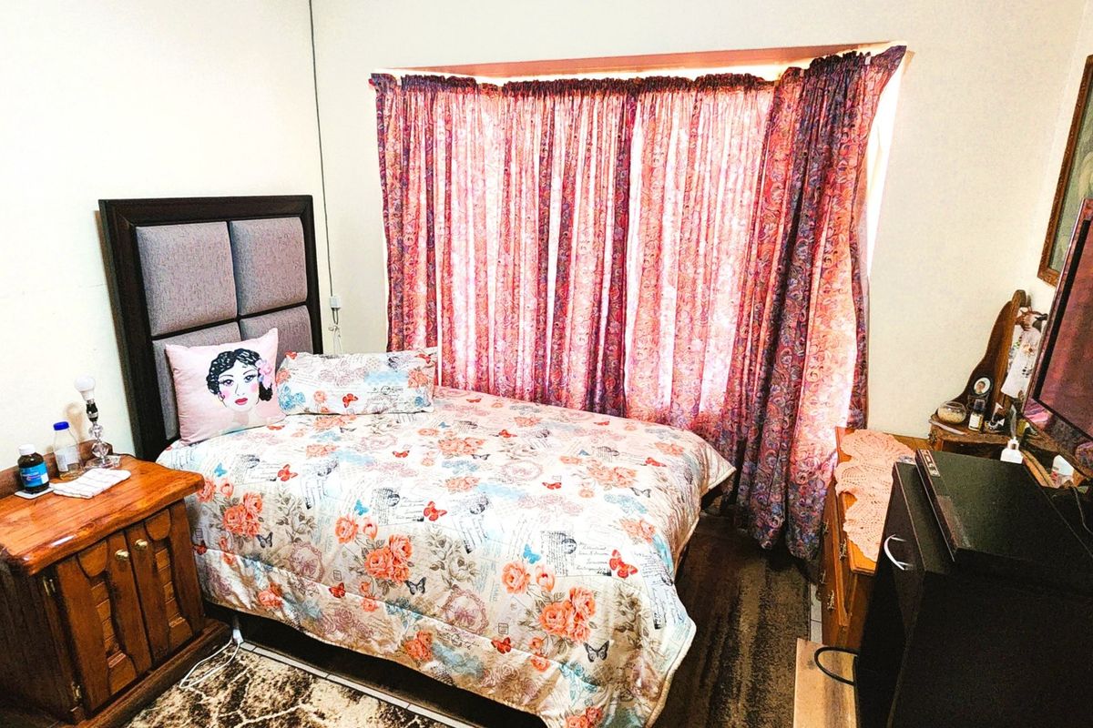 A functional bedroom featuring a window with curtain treatments, providing a comfortable space for rest.