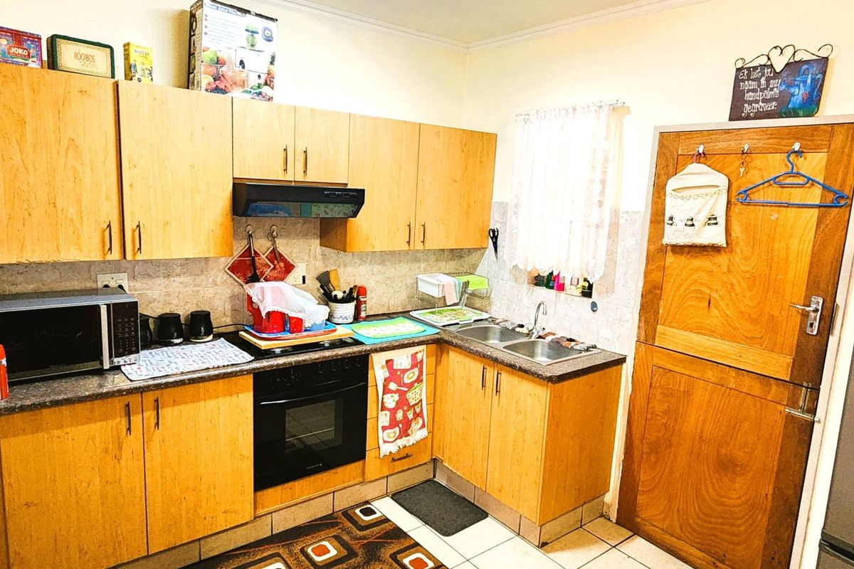 A functional kitchen featuring light wood cabinetry, laminate countertops, a built-in oven with extractor fan, and a classic stable door.