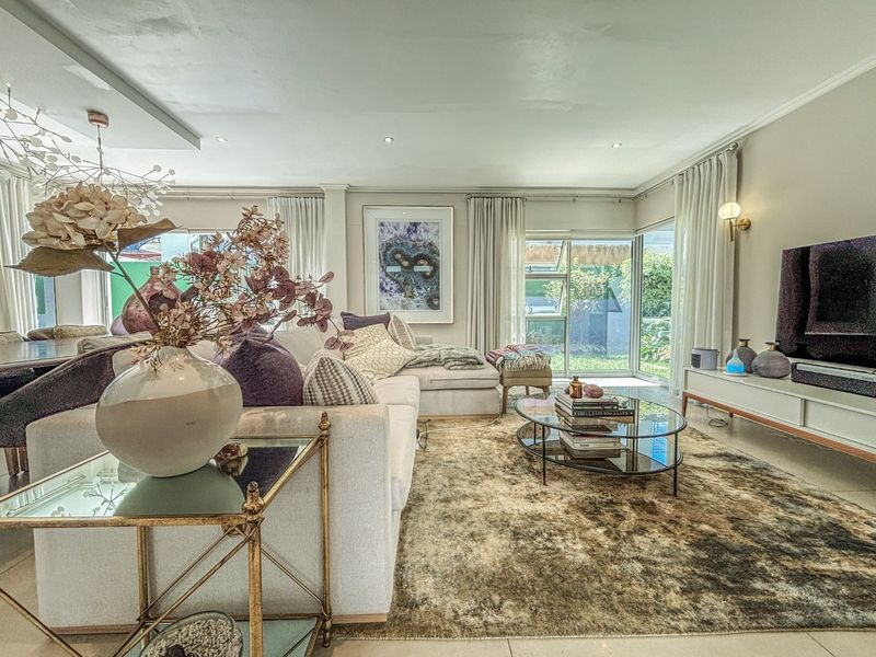 A bright and well-maintained living room featuring tiled floors, recessed lighting, and large sliding glass doors that provide access to the garden.