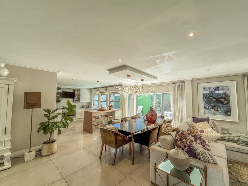 Spacious open-plan living, dining, and kitchen area featuring large porcelain floor tiles, modern cabinetry, and seamless access to the outdoor patio.