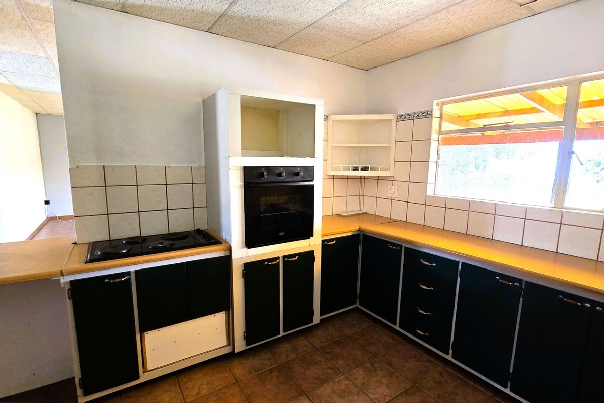 A dated kitchen featuring built-in oven, hob, tiled backsplash, and laminate countertops, requiring cosmetic updates to modernize the space.