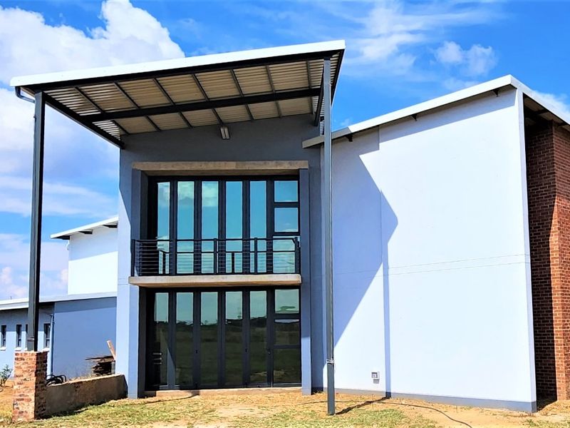 Modern rear elevation featuring a covered patio, upper-level balcony, large aluminium stacking doors, and a combination of brick and rendered wall finishes.