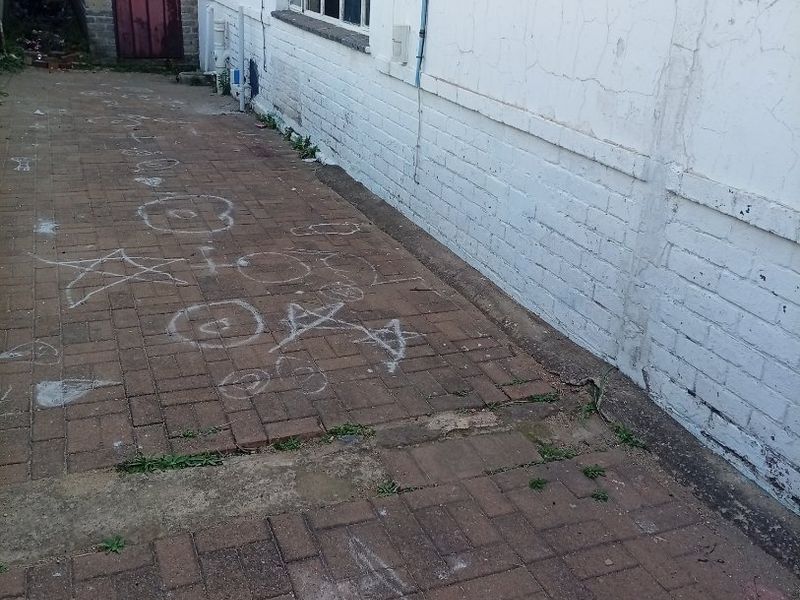 A side or rear exterior area featuring brick paving and a painted brick wall with visible signs of wear and weathering.