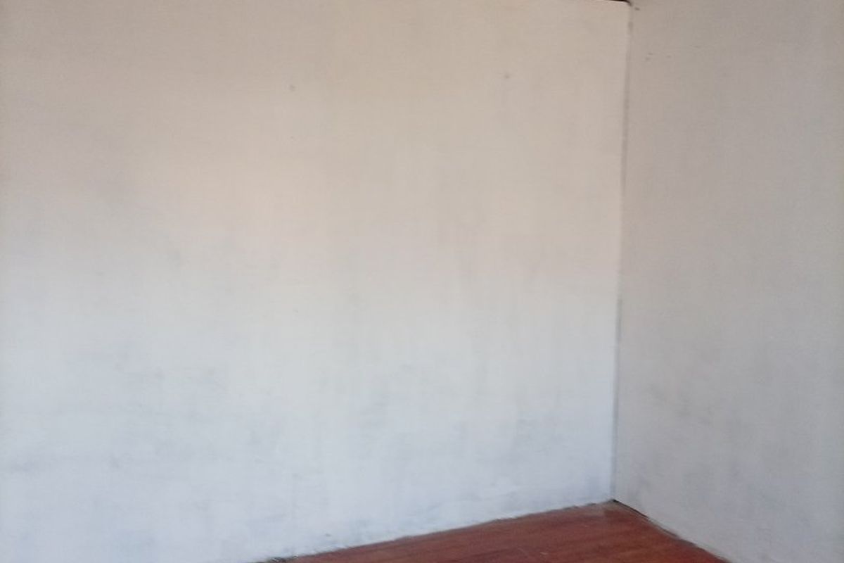 An empty bedroom featuring original timber flooring and a decorative pressed metal ceiling, requiring cosmetic updates to restore its character.