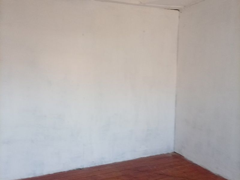 An empty bedroom featuring original timber flooring and a decorative pressed metal ceiling, requiring cosmetic updates to restore its character.