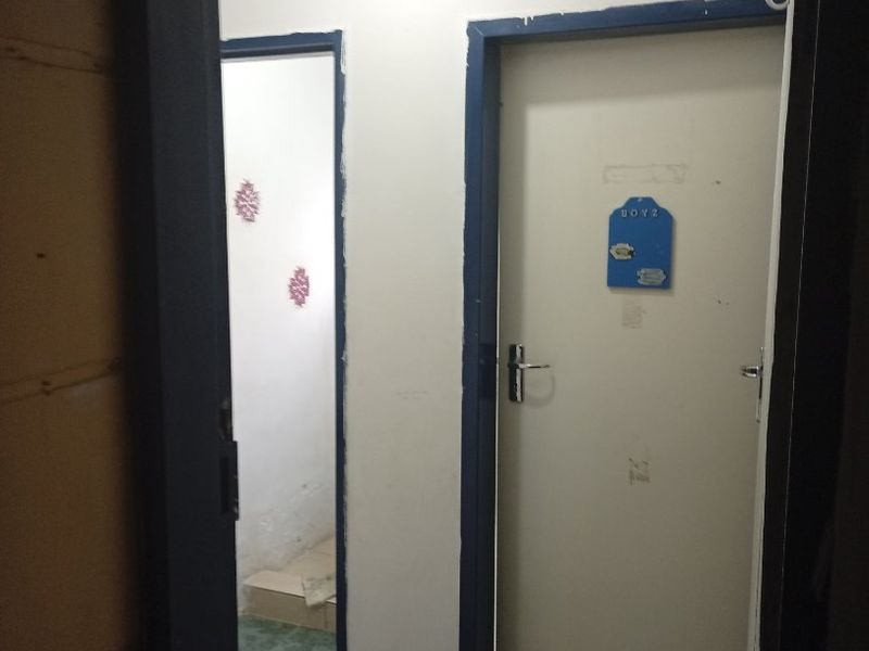 A narrow hallway featuring tiled flooring and two internal doors with dark blue painted frames.