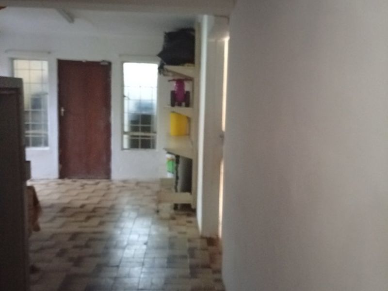 A simple hallway featuring tiled flooring and built-in shelving, leading towards an exterior door.