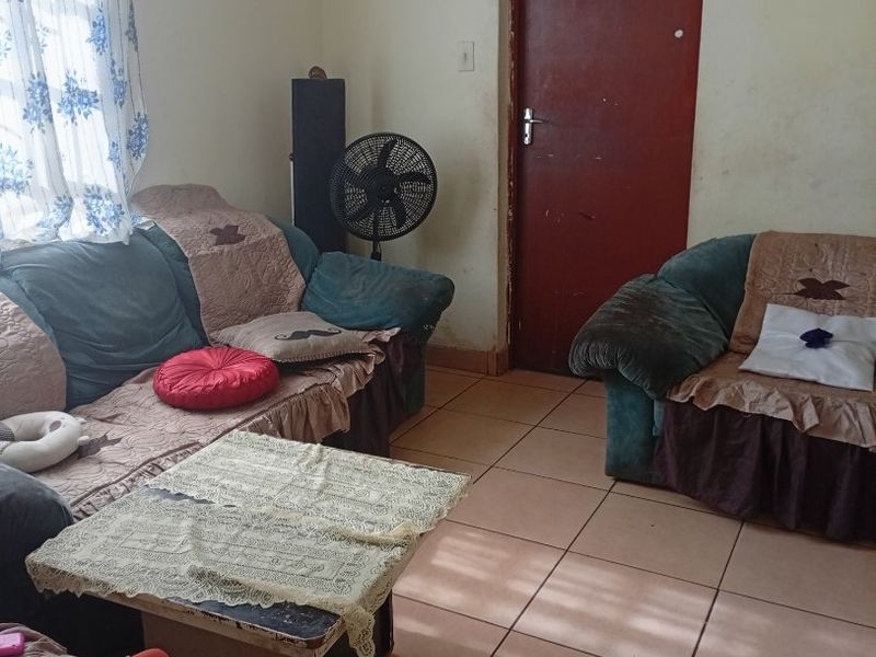 A living room area featuring tiled flooring and a standard interior door, requiring cosmetic updates to improve the overall aesthetic and condition.