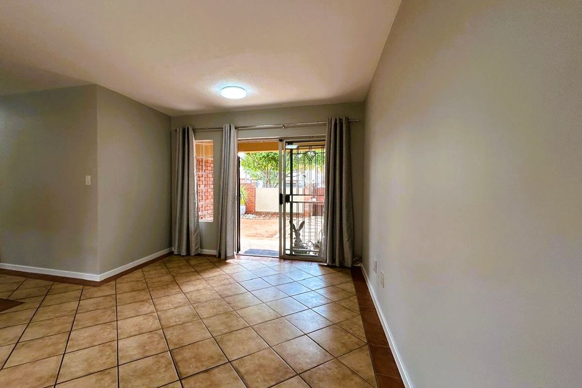 An empty living room featuring ceramic tile flooring and a sliding glass door providing access to the outdoor area.
