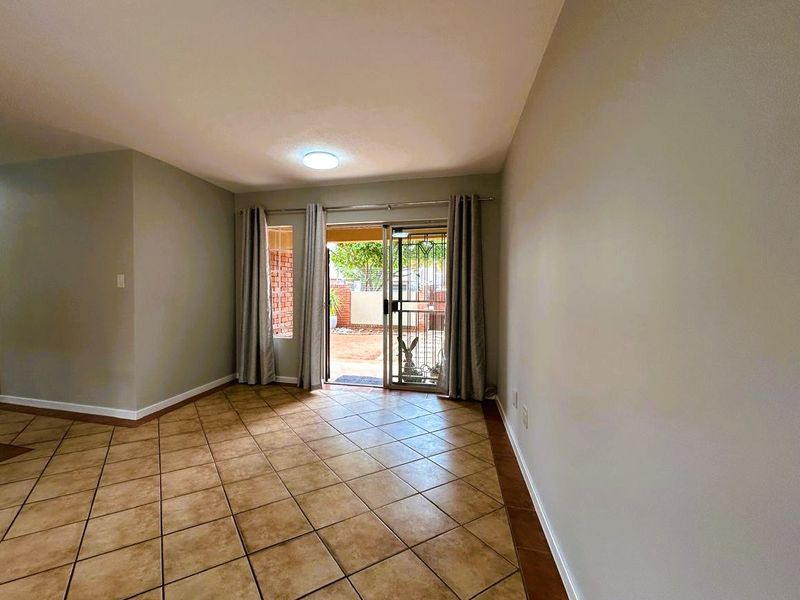 An empty living room featuring ceramic tile flooring and a sliding glass door providing access to the outdoor area.