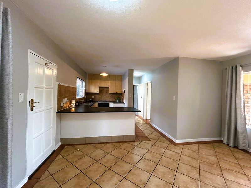 Open-plan living area featuring a functional kitchen with built-in cabinetry, oven, hob, and tiled flooring throughout the space.