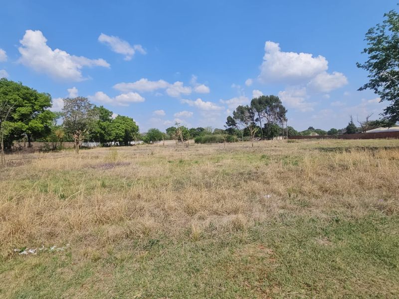 A spacious, level residential vacant land plot featuring established trees and natural grass cover, offering a blank canvas for future development.