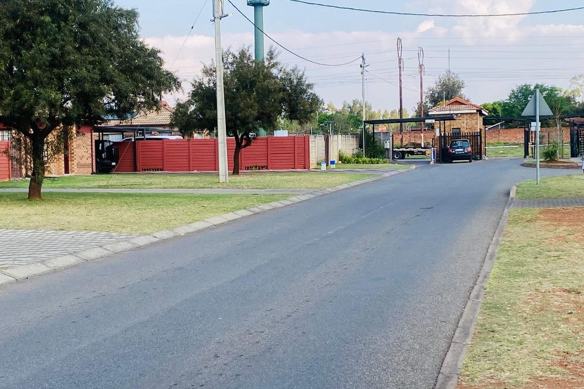 A view of the street approach leading to the residential estate entrance and security gatehouse.