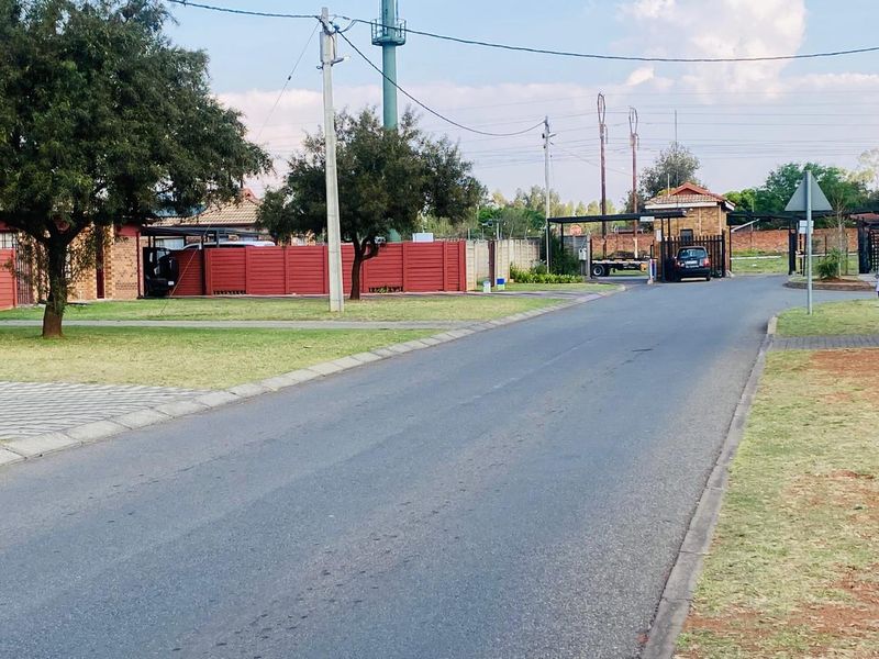 A view of the street approach leading to the residential estate entrance and security gatehouse.